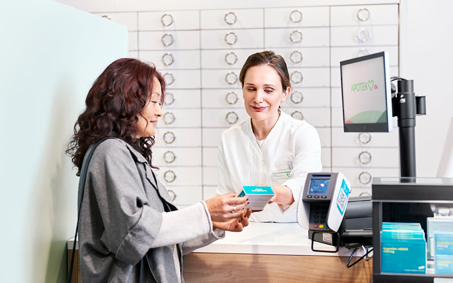 En kund står vid kassan och får rådgivning av en farmaceut.