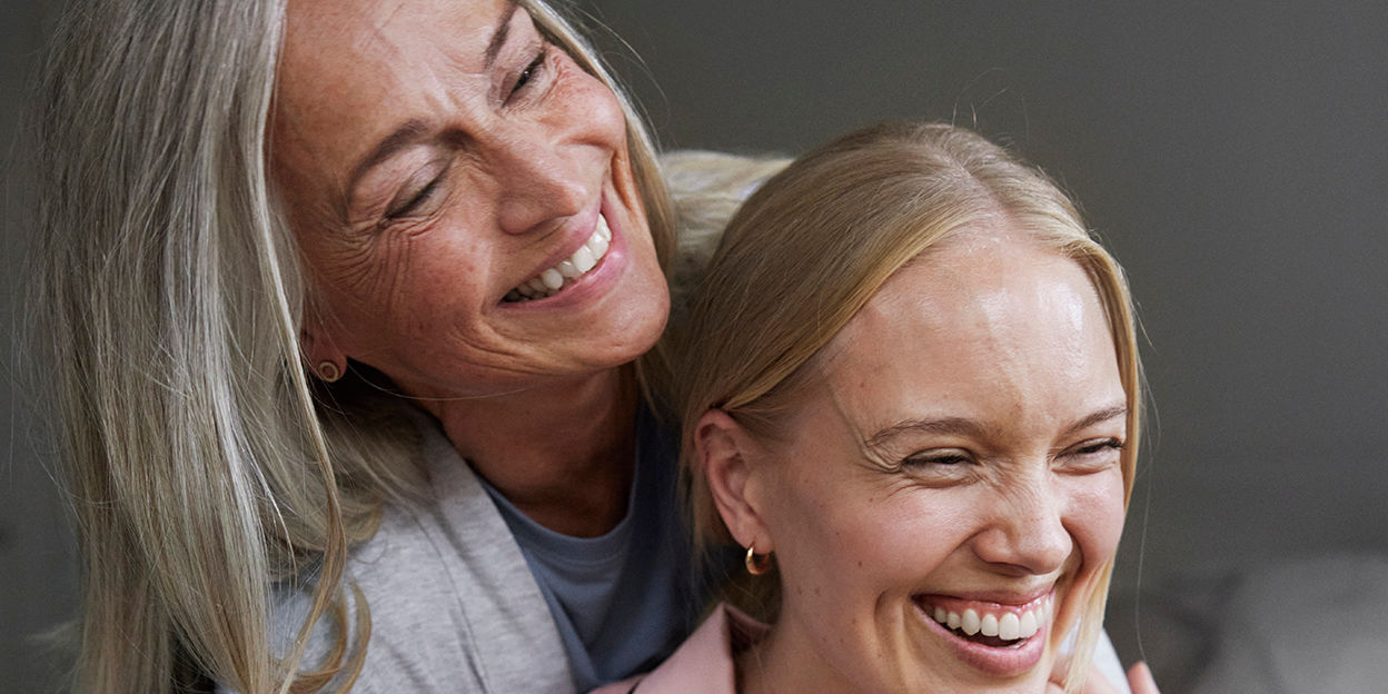 Mamma och dotter ler och kramar varandra. 
