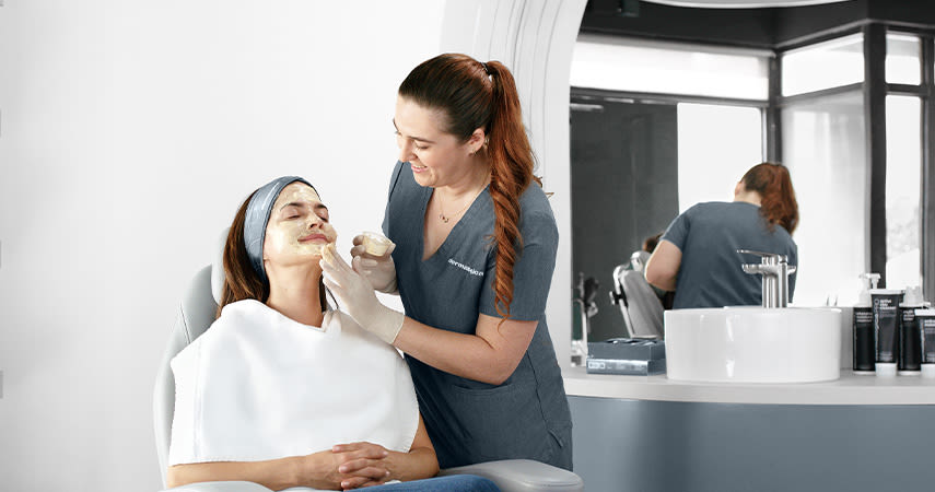 En lycklig kvinna sitter och får en ansiktsbehandling på en salong.