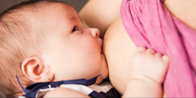 En bebis ammar vid sin mammas bröst.