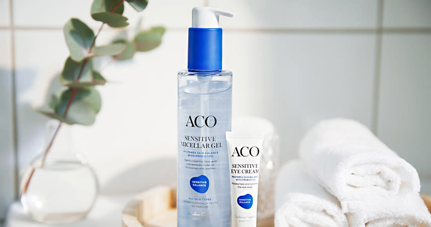 I badrummet står två produkter från ACO:s Sensitive-sortiment. Bredvid ligger vita handdukar och en liten vas med eucalyptus.