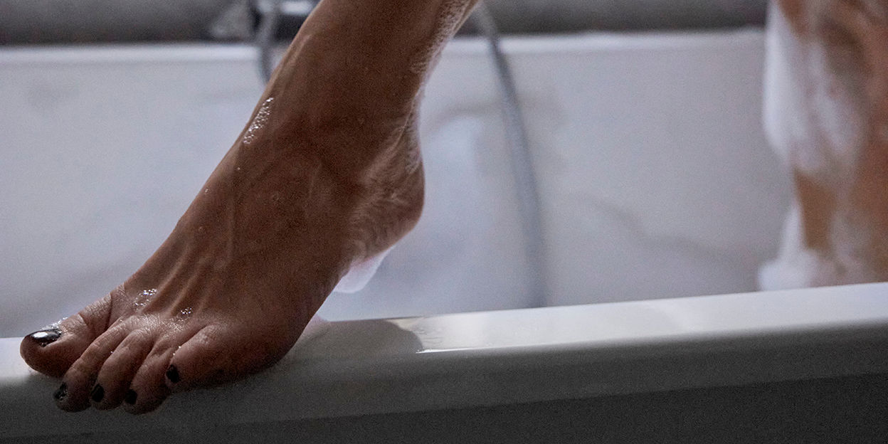 Fot står på badkarskant. 