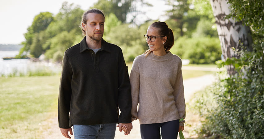 Man och kvinna är ute och promenerar i naturen och håller hand.
