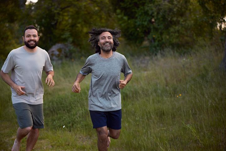Två män är ute och joggar. De springer bredvid varandra och ser glada ut.