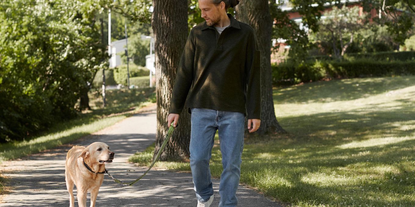Man är ute och promenerar med hund i koppel.