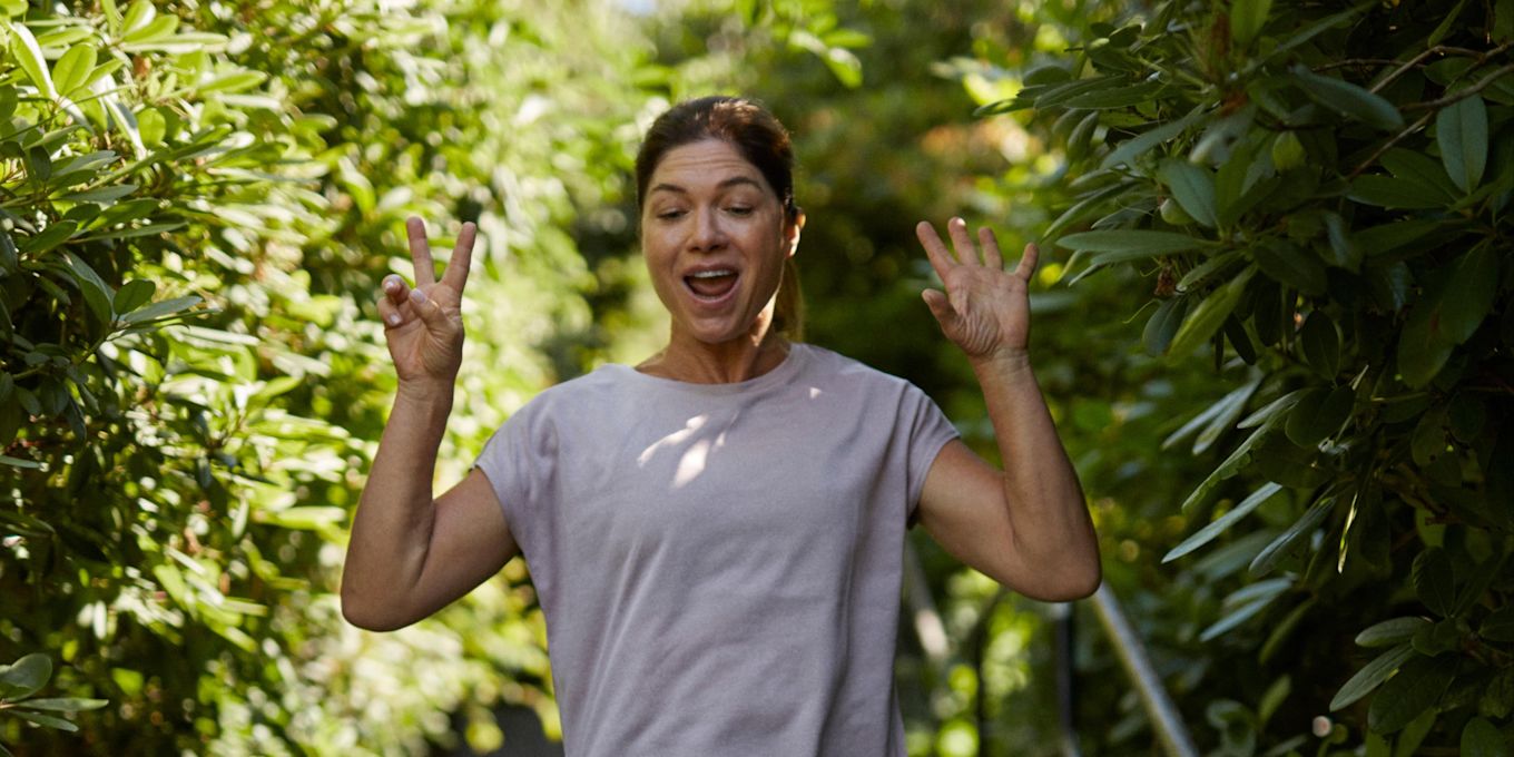 Kvinna springer utomhus nedför en trappa och gör vinnar-tecken med sina fingrar.