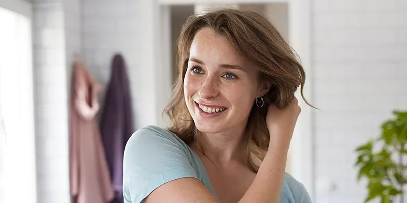 En tjej fixar håret i ett badrum.